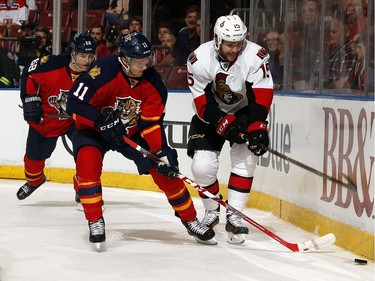 Jonathan Huberdeau #11 of the Florida Panthers digs the puck out from the boards against Zack Smith #15 of the Ottawa Senators.