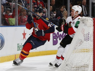 Erik Gudbranson #44 of the Florida Panthers gets hit by the stick of Chris Neil #25 of the Ottawa Senators behind the net during second period action.