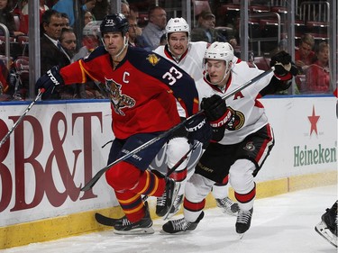 Kyle Turris #7 and Mark Stone #61 of the Ottawa Senators defend against Willie Mitchell #33 of the Florida Panthers as he skates after a loose puck during second period action.