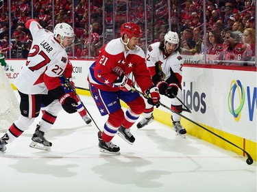Brooks Laich #21 of the Washington Capitals battles to control the puck along the boards against Curtis Lazar #27 and Jared Cowen #2 of the Ottawa Senators in the first period.