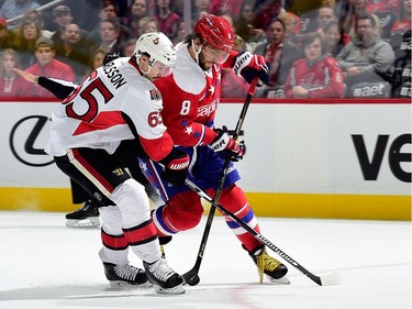 Alex Ovechkin #8 of the Washington Capitals and Erik Karlsson #65 of the Ottawa Senators battle for the puck in the first period.