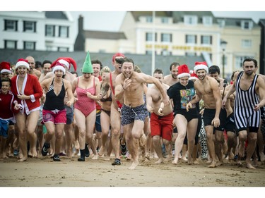 People take part in the annual Exmouth Christmas day swim, at Exmouth beach, in Devon, England, Friday Dec. 25, 2015.