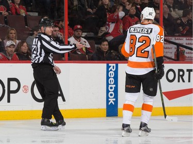 After scoring his first career NHL goal, Evgeny Medvedev #82 of the Philadelphia Flyers retrieves the puck from linesman Vaughan Rody.