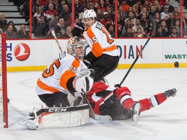 Kyle Turris #7 of the Ottawa Senators falls into Steve Mason #35 of the Philadelphia Flyers as Michael Del Zotto #15 looks on.