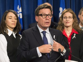 Quebec Interim Public Security Minister Pierre Moreau speaks at a news conference after he tabled legislation creating a gun registry, Thursday, December 3, 2015 at the legislature in Quebec City. Moreau is flanked by Polytechnique victim Nathalie Provost, left, and Heidi Rathjen.