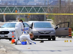 Police forensics officer swabs blood from Temblay Road as they investigate the May 3 shooting death of Sharif Said.