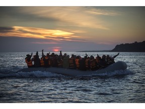 Refugees and migrants calls the attention of a rescue team when approaching the Greek island of Lesbos on a dinghy, after crossing a part of the Aegean sea from Turkey, on Friday, Dec. 25, 2015. The International Organization for Migrants said more than 1 million people have entered Europe earlier this week. Almost all came by sea, while 3,692 drowned in the attempt.(AP Photo/Santi Palacios)