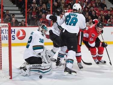 Mark Stone #61 of the Ottawa Senators looks for a rebound as Alex Stalock #32 of the San Jose Sharks makes a save behind teammate Brent Burns #88.