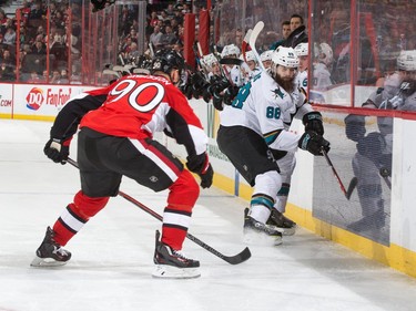 Brent Burns #88 of the San Jose Sharks chips the puck up the boards away from Alex Chiasson #90 of the Ottawa Senators.