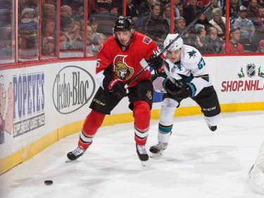 Patrick Wiercioch #46 of the Ottawa Senators controls the puck behind the net as Tommy Wingels #57 of the San Jose Sharks lays chase.