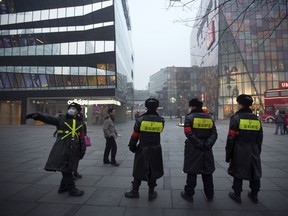 Security guards wearing face masks stand outside a shopping mall in Beijing Friday, Dec. 25, 2015. Security remained elevated in parts of Beijing on Friday, a day after the U.S. and other foreign embassies in China warned of potential threats to Westerners around the Christmas holiday.