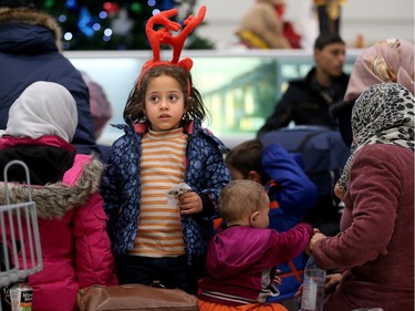 Six-year-old Sedra Joudi, who had just arrived with her family of eight from Syria, wears her new gift of reindeer antlers as the family waited for their bags.  A couple of dozen Syrian refugees, who seemed tired but happy,  arrived at Ottawa's airport Tuesday (Dec. 29, 2015) to a welcoming group of volunteers handing out gifts. The group was taken from the airport in a bus to downtown, but not before feeling the chill of the capital's first winter snowstorm.