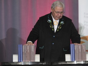 Commissioner Justice Murray Sinclair pauses and places his hands on the final report of the Truth and Reconciliation commission following its unveiling, Tuesday December 15, 2015 in Ottawa. THE CANADIAN PRESS/Adrian Wyld