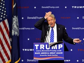 In this Thursday, Aug.  27, 2015 file photo, Republican presidential candidate Donald Trump pulls his hair back to show that it is not a toupee while speaking during a rally at the TD Convention Center in Greenville, S.C. (AP Photo/Richard Shiro)
