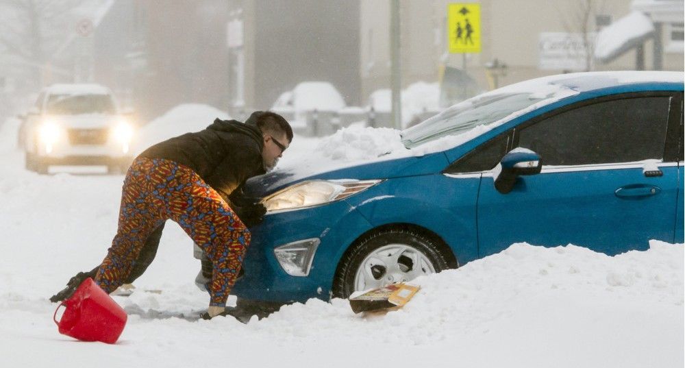 Two men try to free a car from a driveway off Churchill Ave after a heavy snowfall hit the capital region Tuesday December 29, 2015.