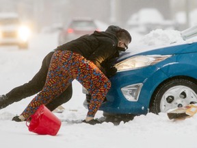 Two men try to free a car from a driveway off Churchill Ave after a heavy snowfall hit the capital region Tuesday.