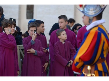 An altar boy takes a picture of a Swiss guard before the arrival of Pope Francis for the traditional "Urbi et Orbi" Christmas message to the city and the world, on December 25, 2015 at St Peter's square in Vatican. Pope Francis was expected to appeal for reconciliation of fractured communities in his Christmas Day blessing Friday, as the world takes stock of a year of violence and suffering that saw hundreds of thousands flee their homes.