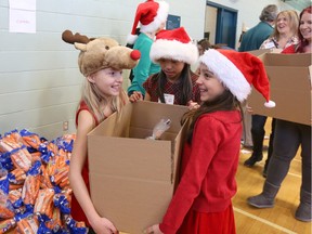 Volunteers Emma Parkinson (L), 9,  Leanne Luo (M), 9, and Kierra Duncan (R), 9, helpto  pack 400 hampers to deliver to families in need with the Caring and Sharing Exchange in Ottawa on December 19, 2014. (Jana Chytilova / Ottawa Citizen) ORG XMIT: 1218-Hampers07