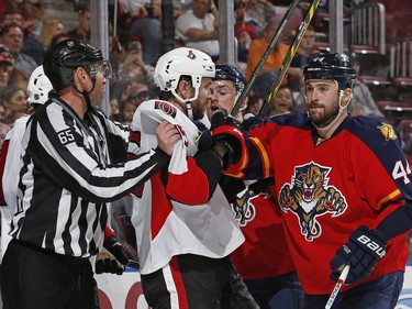 Linesman Pierre Racicot restrains Ottawa Senators center Zack Smith (15) as he comes together with Florida Panthers defenseman Erik Gudbranson (44) behind the net during the second period.