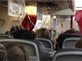 Passengers sit with oxygen masks deployed on an Air Canada flight Dec. 19. The plane made an emergency landing in Albuquerque,