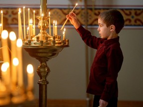 A young boy lights a candle for the living and the dead as a means of paying homage to both at the front of the church upon entering. Christ the Saviour Orthodox Church held their Christmas service.
