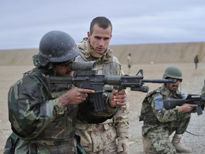 In this 2011 photo taken at Kandahar Airfield, Afghanistan MCpl Dion Sylvain, Kandak Mentor Team (KMT) 4 Recce Coy mentors Afghan National Police members (ANP) at Camp Hero on a live fire exercise. DND photo.