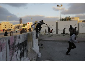 Bahraini protesters jump a cement barricade as police approach near the end of a march denouncing the execution of Saudi Shiite cleric Sheikh Nimr al-Nimr, on Sunday, Jan. 3, 2016.