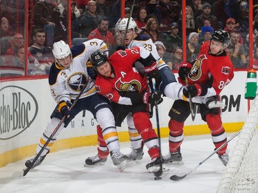 Chris Neil #25 and Max McCormick #89 of the Ottawa Senators battles for puck possession against Mark Pysyk #3 and Jake McCabe #29 of the Buffalo Sabres.