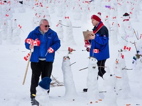 Councillors Allan Hubley, left, and Tim Tierney help count snowmen on the field at TD Place stadium.