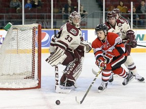 Dante Salituro of the Ottawa 67's reaches for the puck while Peterborough Petes goalie Matthew Mancina and Eric Cornel look on.