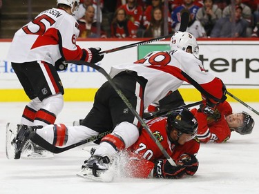 Ottawa Senators defenseman Fredrik Claesson (49) falls over Chicago Blackhawks left wing Dennis Rasmussen (70) during the second period of an NHL hockey game Sunday, Jan. 3, 2016, in Chicago.