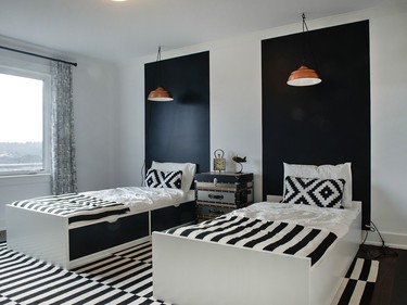 The boys’ room in the St. James is fun with bright white walls and graphic geometric detailing in the fabrics. A painted black stripe behind each bed creates an instant headboard, while copper plug-in lighting that stands out against the black highlights each bed.