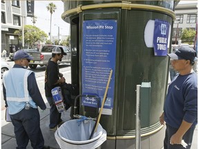 In this Thursday, July 30, 2015, photo an attendant looks on as a man enters a Pit Stop public toilet outside a Mission District transit station in San Francisco. The Pit Stop, located by a public wall covered with a repellant paint that makes pee spray back on the offender, is a project operated by San Francisco Public Works that provides portable toilets and sinks and is part of the city's latest attempt to clean up urine-soaked alleyways and walls.