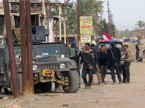 Iraqi security forces stand next to their vehicles as they clear al-Sajarya district on the eastern outskirts of Ramadi, the capital of Anbar province, on January 17, 2016, a few weeks after declaring victory against the Islamic State (IS) group.  / AFP / MOADH AL-DULAIMIMOADH AL-DULAIMI/AFP/Getty Images