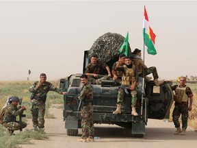A file picture taken in 2015, shows Iraqi Kurdish Peshmerga fighters posing for a photo next to a military vehicle bearing the Kurdish flag.
