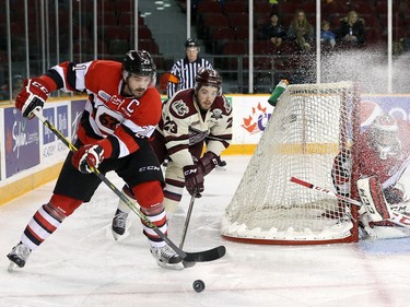 Jacob Middleton #21 of the Ottawa 67's uses his body to protect the puck from a forechecking Hunter Garlent #23 of the Peterborough Petes as Leo Lazarev #37 of the Ottawa 67's defends the net.