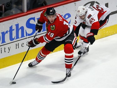 Chicago Blackhawks center Jonathan Toews (19) looks to pass the puck as Ottawa Senators defenseman Erik Karlsson (65) defends during the third period of an NHL hockey game Sunday, Jan. 3, 2016, in Chicago. The Blackhawks won the game 3-0.