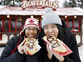Kay Fung, left, and Gigi Tuet, both from Vancouver, enjoy some BeaverTails Thursday. BeaverTails crews, meantime, were gearing up for what they expect will be a busy weekend. The  Rideau Canal will be open to skaters, if weather permits.