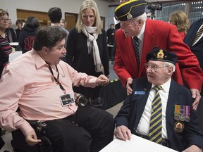 Veteran Affairs Minister Kent Hehr, left, chats with veterans as Environment Minister Catherine McKenna, centre, looks on, at a local community centre in St. Andrews, N.B., on Monday, Jan. 18, 2016.