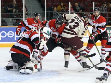 Nevin Guy #24 of the Ottawa 67's ties up Hunter Garlent #23 of the Peterborough Petes during a scramble in front of Leo Lazarev #37 of the Ottawa 67's.