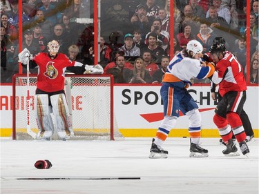 Mark Borowiecki #74 of the Ottawa Senators squares off with Matt Martin #17 of the New York Islanders for a first period fight as Andrew Hammond #30 looks on from his crease.