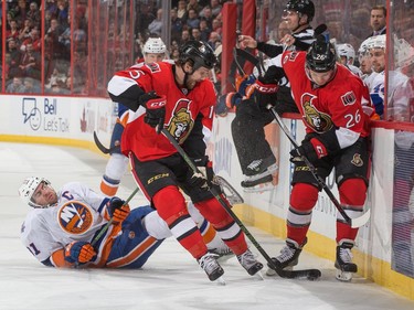Zack Smith #15 and Matt Puempel #26 of the Ottawa Senators control the puck along the boards as John Tavares #91 of the New York Islanders falls to the ice.