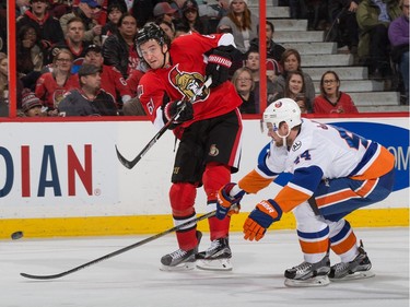 Mark Stone #61 of the Ottawa Senators shoots the puck against Calvin de Haan #44 of the New York Islanders.