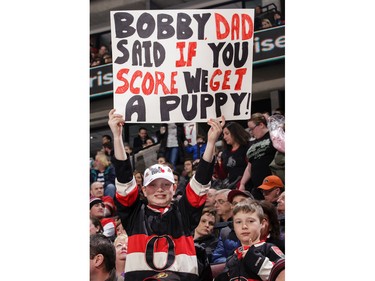 A couple of young fans hold up a sign with a promise of a puppy during an NHL game between the Ottawa Senators and the New York Rangers at the Canadian Tire Centre on Sunday, Jan. 24, 2016.