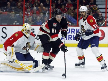 Ottawa Senators' Mark Stone (61) grabs a loose puck in front of Florida Panthers' goalie, Roberto Luongo (1) while Willie Mitchell (33) looks on during the first period.