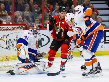 Ottawa Senators right wing Chris Neil (25) looks for a rebound as New York Islanders right wing Kyle Okposo (21) clears the puck from in front of New York Islanders goalie Jaroslav Halak (41).