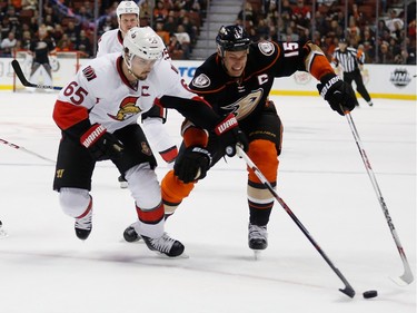 ANAHEIM, CA - JANUARY 13:  Ryan Getzlaf #15 of the Anaheim Ducks and Erik Karlsson #65 of the Ottawa Senators skate to a loose puck during the first period of a game at Honda Center on January 13, 2016 in Anaheim, California.