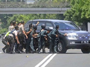 Police officers take cover behind a vehicle during a gun battle with attackers near the site where an explosion went off in Jakarta, Indonesia Thursday, Jan. 14, 2016. Attackers set off explosions at a Starbucks cafe in a bustling shopping area in Indonesia's capital and waged gunbattles with police Thursday, leaving bodies in the streets as office workers watched in terror from high-rise windows. (AP Photo)