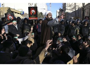 Surrounded by policemen, a Muslim cleric addresses a crowd during a demonstration to denounce the execution of Saudi Shiite Sheikh Nimr al-Nimr, seen in poster, in front of the Saudi embassy in Tehran, Iran, Sunday, Jan. 3, 2016. Saudi Arabia announced the execution of al-Nimr on Saturday along with 46 others. Al-Nimr was a central figure in protests by Saudi Arabia's Shiite minority until his arrest in 2012, and his execution drew condemnation from Shiites across the region.
