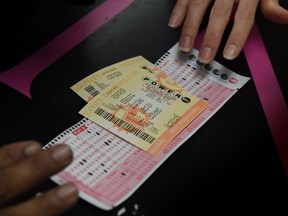 A customer picks up her California Powerball lottery tickets at the famous Bluebird Liquor store which is considered to be a lucky retailer of tickets, in Hawthorne, California on January 13, 2016. Record sales drove up the largest jackpot in US history to a whopping $1.5 billion as people dreaming of riches flocked across state lines and international borders to buy tickets. /